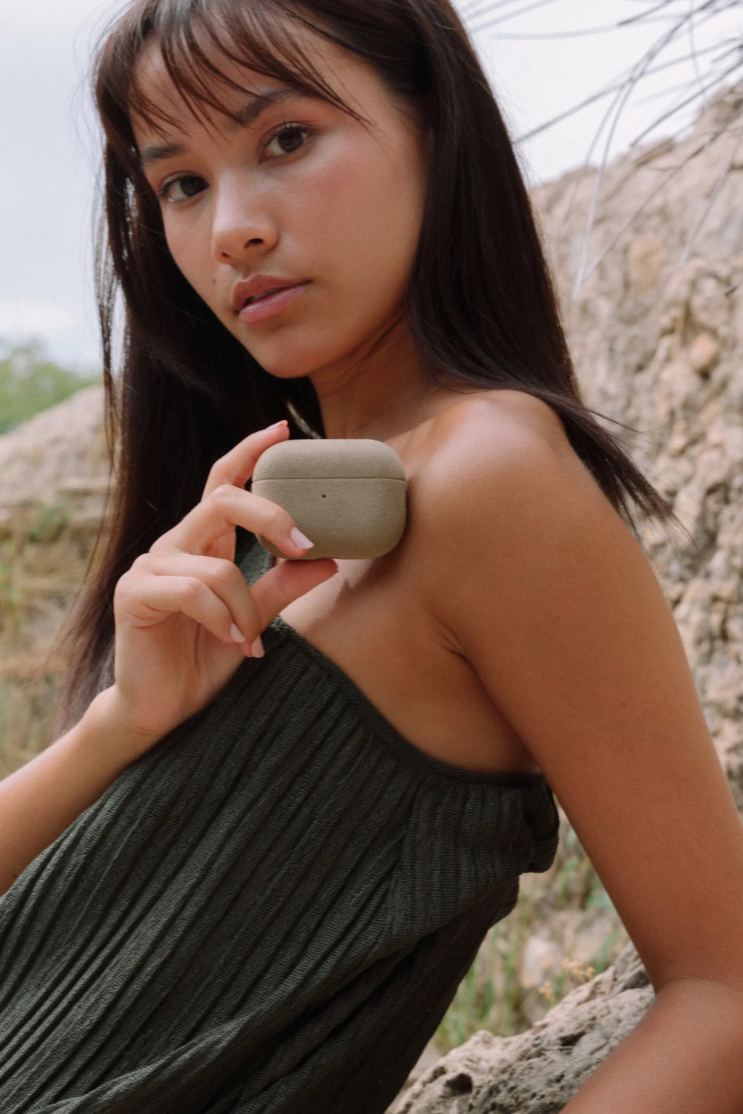 Woman holding Luriax Alcantara AirPods case outdoors