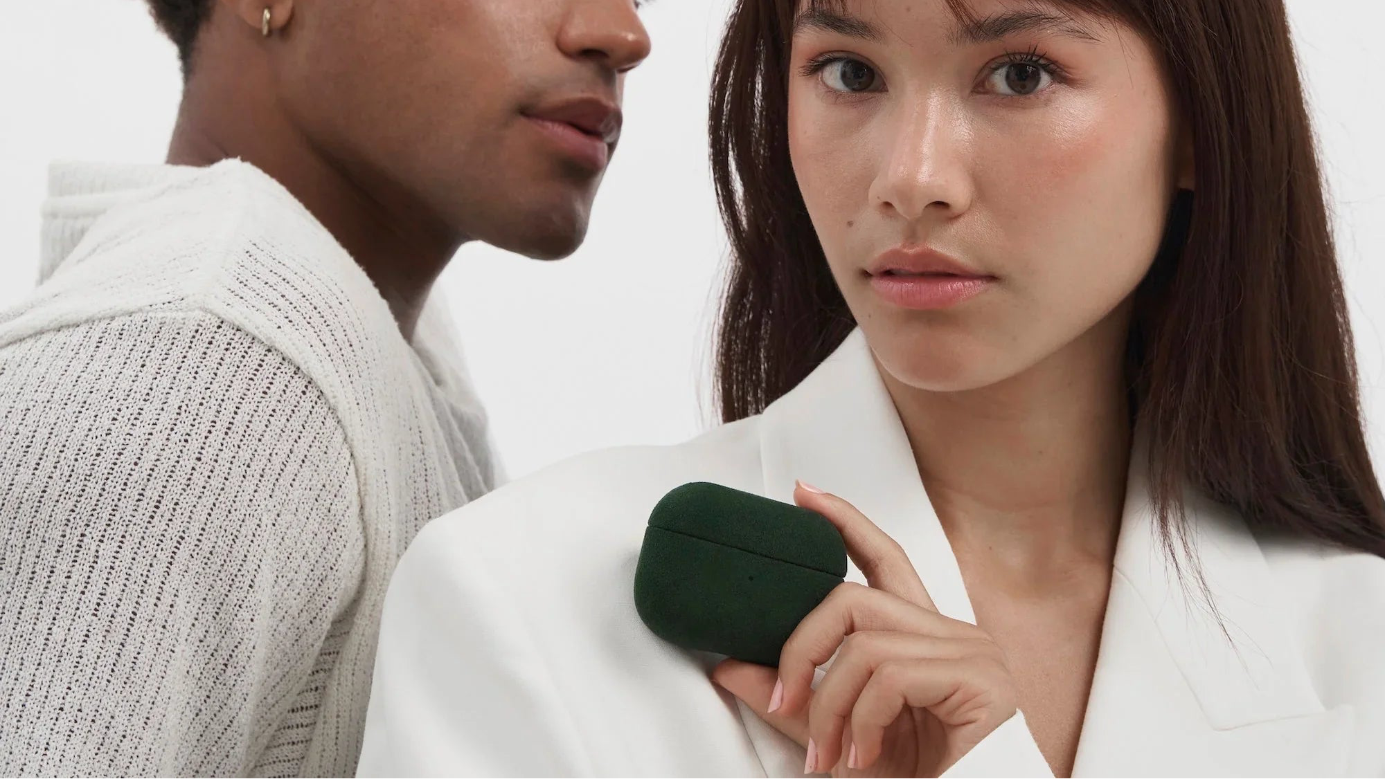 Luriax British Racing Green Alcantara AirPods case, suede-like texture, held by woman in white blazer